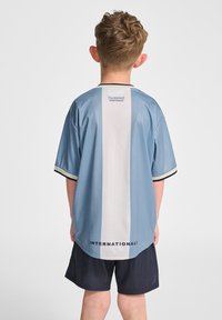 Ljusblå sporttröja med vit vertikal rand, svarta detaljer och "INTERNATIONALS" tryckt längst ner, tillverkad av slätt tyg.
