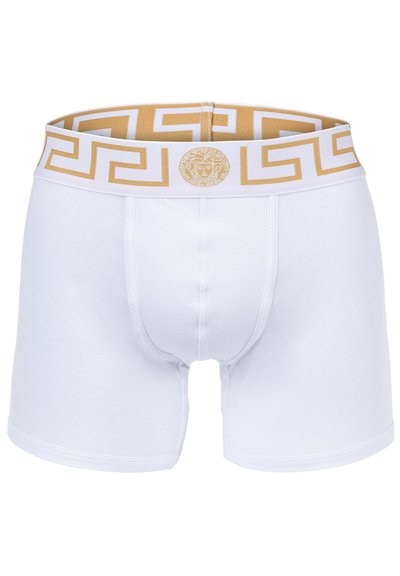 White boxer shorts with a gold and white Greek key pattern on the waistband, featuring a round logo detail. Soft cotton material.