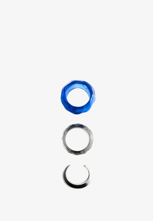 Tre anelli circolari su sfondo bianco: blu testurizzato, grigio sfaccettato e anello aperto in metallo argento.