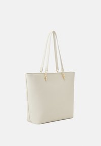 Ljust beige toteväska med dubbla handtag, slät textur, minimalistisk design och detaljer i guldton.