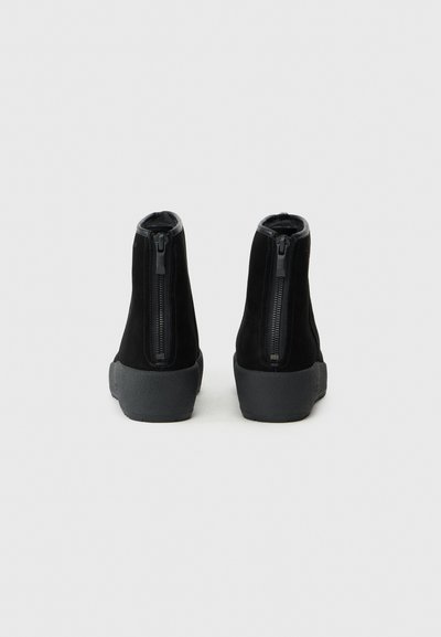 Juodos suede apyrankių batai su lygia juoda užtrauktuko detalė, tekstūruota guma padu ir minimalistišku dizainu.