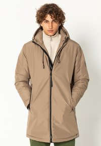 Beige Daunenjacke mit Kapuze, Frontreißverschluss und schwarzen Akzenten. Sie verfügt über eine glatte Textur und elastische Kordelzüge zur Anpassung.