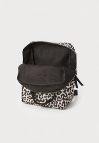Leopardmønstret ryggsekk med svart klaff og fôr. Har en glidelåslukking og topphåndtak. Teksturert stoff med et slitesterkt design.