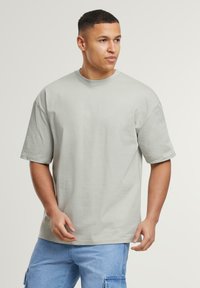 Lys grå oversized t-shirt i bomuld med korte ærmer, rund hals og en glat tekstur. Designet til en afslappet pasform.