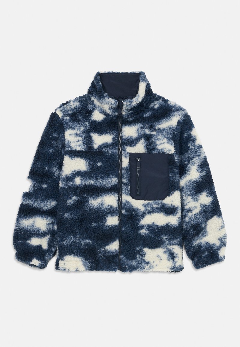 Tkanina polarowa w granatowo-kremowym wzorze tie-dye, z wysokim kołnierzem, pełnym zapięciem na zamek oraz kieszenią na zamek na piersi.