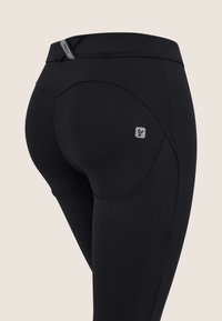 Mustat leggingsit, joissa on tyylikäs muotoilu, taustalla kaareva sauma, logo-patch ja joustava vyötärö mukavuutta varten.