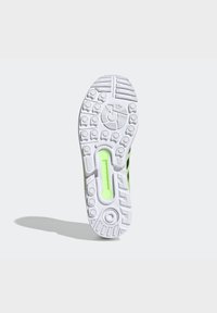 Shoe sole with intricate white rubber patterns, featuring a translucent green accent and textured grip for traction.