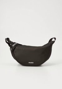 Black fabric waist bag with a crescent shape, featuring a white logo and adjustable strap with text. Smooth texture, minimalistic design.