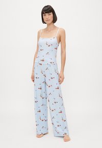 Niebieski zestaw piżamowy w kwiatowy wzór, wykonany z lekkiego materiału. Składa się z dopasowanego topu na ramiączkach i spodni o szerokich nogawkach.