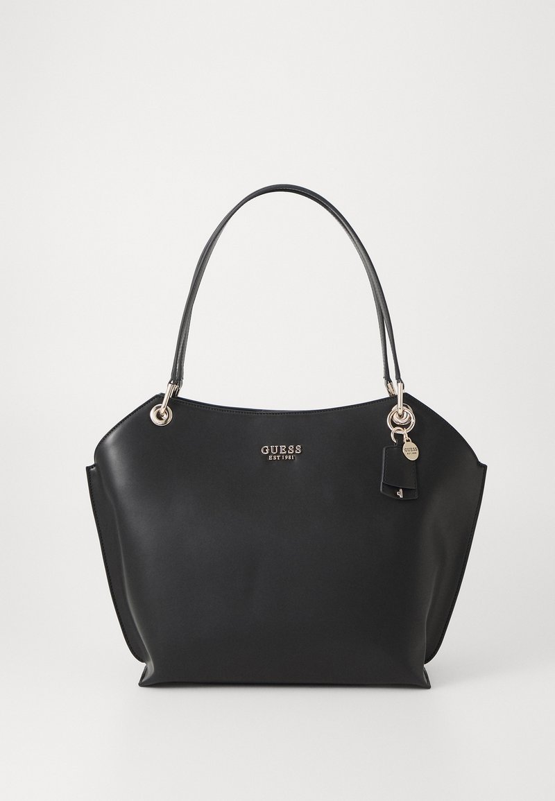 Svart tote-veske i kunstlær med en glatt tekstur, metalliske detaljer og logo. Har to skulderstropper og en charm-pendant.