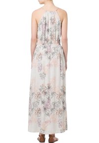 Robe maxi en tissu léger, avec un motif floral en rose et violet. Le dos a de fines bretelles et un élastique au niveau de la taille.