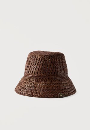 Dark brown woven straw bucket hat with a wide brim and small heart-shaped metal tag on the side.
