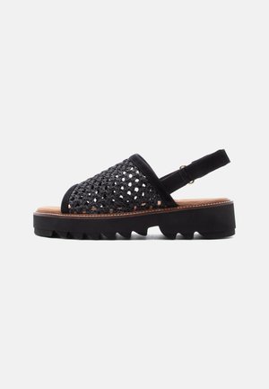 Black open-toe sandal with woven upper, adjustable slingback strap, cushioned insole, and thick, ridged sole for grip and comfort.