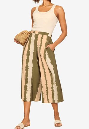 Breda byxor i olivgrön och beige med randigt mönster, ihop med en krämfärgad linne. Har fickor och lättviktsmaterial.