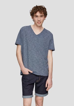 T-shirt bleu à manches courtes et décolleté en V en tissu chiné, associé à un short en denim foncé retroussé aux poignets. Design simple avec coupe décontractée.