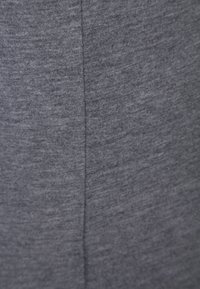 Tissu gris avec une couture verticale descendant du centre, montrant une texture en tricot et un léger motif chiné.