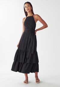 Čierne maxi šaty s viacerými vrstvami, priliehajúcim korzetom, halter výstrihom a opaskom vo farbe s uzlom na páse. Vyrobené z ľahkého materiálu s hladkou textúrou.
