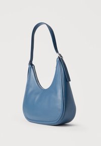 Μπλε δερμάτινη τσάντα ώμου με καμπυλωτό πάνω φερμουάρ και ρυθμιζόμενο ιμάντα, σε λευκό φόντο.