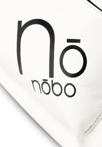 Witte nep leren tas met gedurfde zwarte branding met "nōbō." De textuur is glad met een lichte korrel. Eenvoudig ontwerp, geen extra accenten.