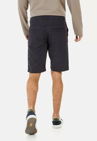 Shorts en coton bleu marine avec une coupe droite, dotés de poches arrière et d'un design simple. Associés à des baskets basses multicolores.
