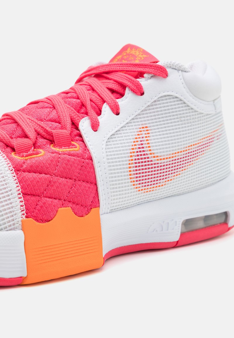 Baskets Nike avec une tige en mesh blanc, des accents rose vif, une texture matelassée sur le côté, et un détail de logo orange sur la pointe.
