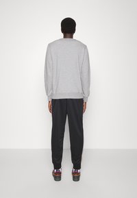 Grå sweatshirt med långa ärmar, rundad halsringning, kombinerad med svarta joggers med sidostrecksdetaljer. Stylad med färgglada sneakers.