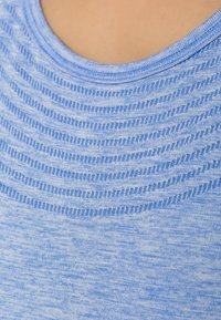 Ljusblått tyg med texturerade horisontella linjer och subtila nyansvariationer. Rund halsringning och mjuk, slät textur.