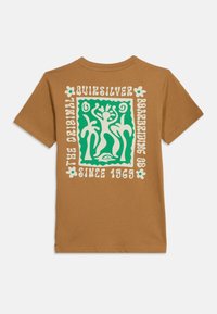 Καφέ T-shirt με πράσινο και κρεμ γραφικό από αφηρημένες φιγούρες και φοίνικες, περιβαλλόμενο από το κείμενο "Quiksilver The Original Surfing Co Since 1969".
