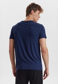 Navy blue t-shirt with short sleeves and a crew neckline. Smooth cotton fabric, fitted design. View from the back, showing shoulder and neck details.