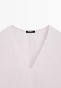 Lyserød hør V-hals beklædningsgenstand med synlige syninger og et sort mærke med teksten "Massimo Dutti Made in China" ved kraven.