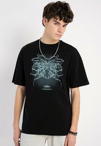 Czarny bawełniany t-shirt z krótkim rękawem, z niebieskim nadrukiem na przodzie, okrągłym dekoltem i luźnym krojem.