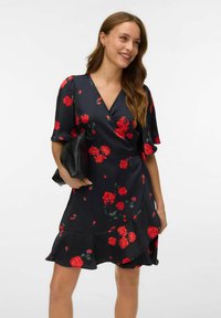 Robe portefeuille noire à motifs floraux avec des roses rouges, manches courtes,ourlet évasé et texture lisse. Associée à une pochette noire.