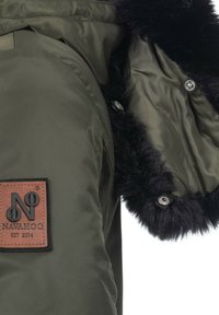 Green padded jacket with a black faux fur trim, featuring a brown logo patch and silver snap buttons along the interior lining.