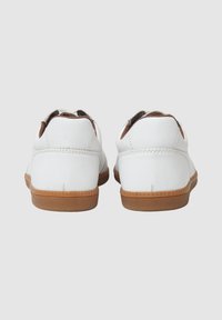 Sneaker bianche in pelle con profilo basso, dettagli marroni e suole in gomma. Texture liscia con dettagli di cucitura sul retro.
