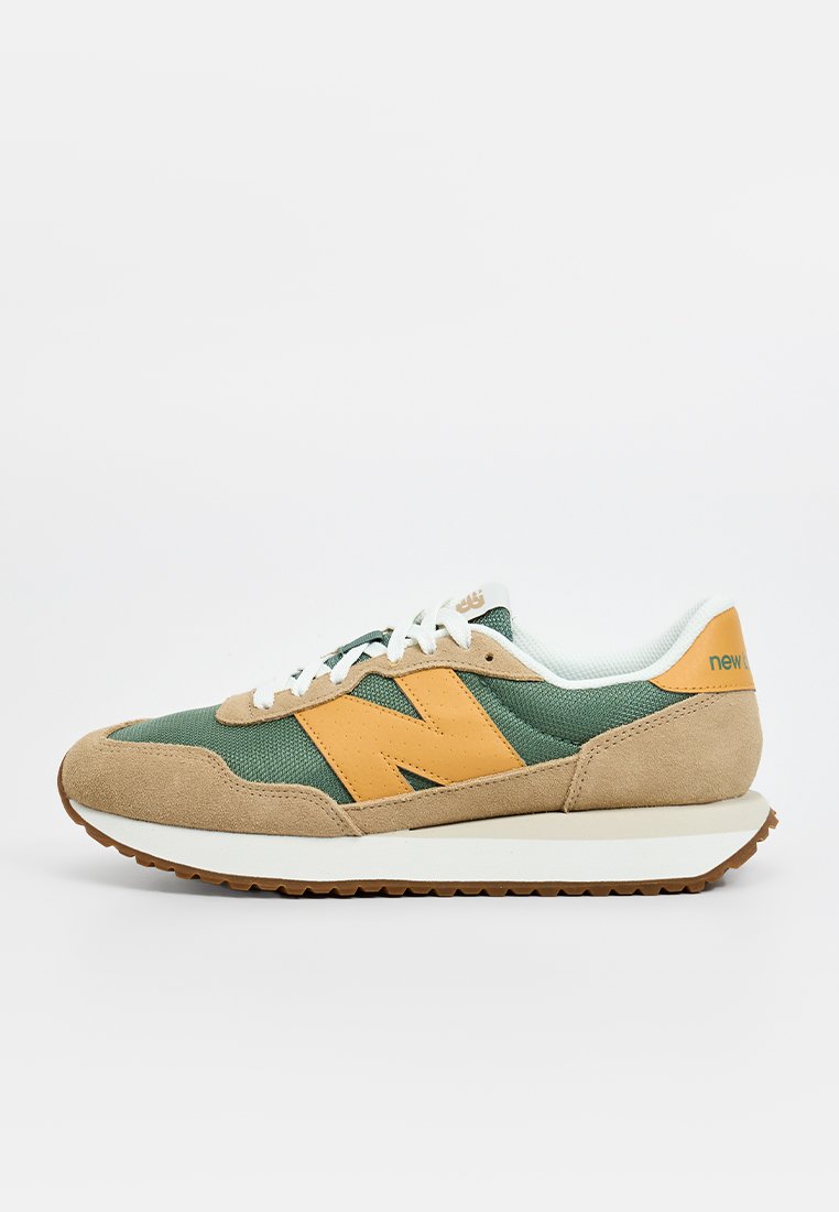 Zapatilla verde y beige con parte superior de ante y malla, que presenta un destacado logo "N" en naranja, cordones blancos y una suela de goma marrón.