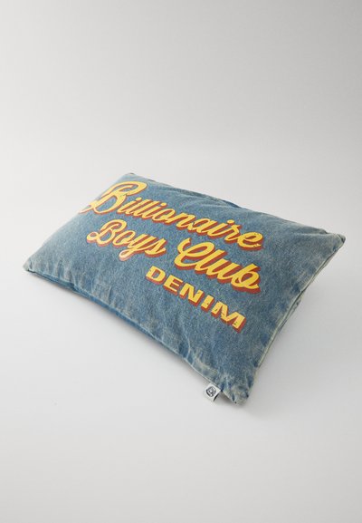 Denimist padjaga, millel on kollase-oranži tikandiga tekst "Billionaire Boys Club" ja "DENIM" sinise kangast tausta vastu. Pehme tekstuur, ristküliku kujuline.