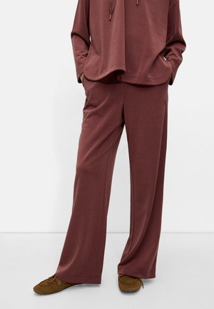 Maroon two-piece lounge set made of soft fabric; relaxed-fit long sleeves with a cropped hem and wide-leg pants, paired with brown slippers.