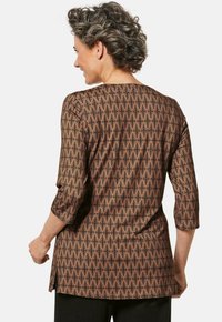 Braun gemusterte Bluse mit geometrischem Design, Dreiviertelärmeln und einer lockeren Passform mit Seitenschlitzen. Glatte Textur.
