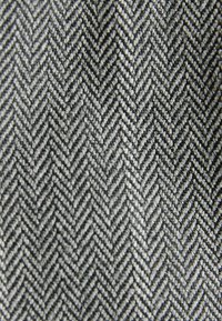 Un tissu à motif chevron dans des nuances de gris, présentant un tissage texturé avec des fils en relief, créant une apparence dimensionnelle.