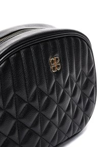 Bolso de imitación cuero negro acolchado con forma redondeada, herrajes dorados y un patrón texturizado con formas de diamante. Cierre de cremallera.