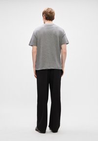 Γκρι βαμβακερό μπλουζάκι κοντομάνικο, σε χαλαρή γραμμή και στρογγυλή λαιμόκοψη, συνδυασμένο με χαλαρές μαύρες παντελόνες. Απλός και χωρίς περιττές λεπτομέρειες σχεδιασμός.