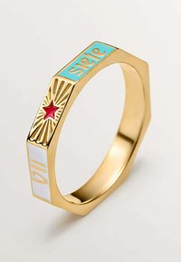 Anillo hexagonal de oro con "suerte" en turquesa, "111" en blanco, y un diseño de explosión estelar roja con rayos en sus superficies planas.