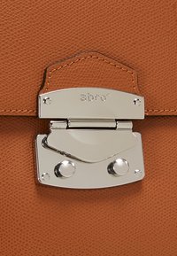 Sac en cuir marron avec une surface texturée, présentant un fermoir en métal argenté et deux attaches rondes. Nom de la marque "abro" embossé sur le fermoir.