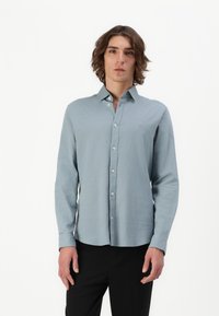 Hellblaues Langarmhemd aus weichem Stoff, mit Button-Down-Kragen, vorderer Knopfleiste und dezentem Logo-Detail auf der Brust.