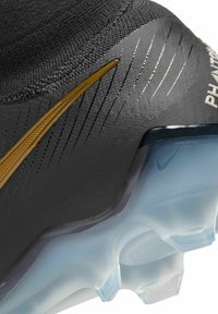 Scarpa da calcio nera con tomaia sintetica testurizzata, accenti dorati e suola traslucida con tacchetti distintivi per una trazione efficace.