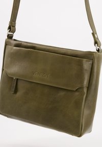 Green leather crossbody bag with a front flap, embossed logo, and a zippered pocket. Features a long adjustable strap and smooth texture.