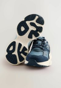 Baskets de sport bleu marine et bleu clair avec tige en mesh, semelle en caoutchouc texturé et système de laçage ; elles comportent un col rembourré et des accents de logo.