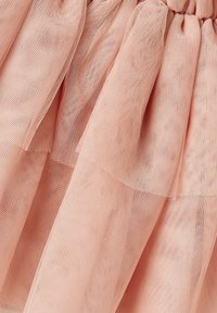 Rosa tylltyg med ett lagerdesign, som har en mjuk textur och en något genomskinlig look, samlad vid midjan.