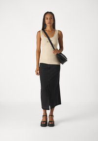 Top de bumbac bej, fustă din denim neagră, până la genunchi, sandale negre cu platformă. Geantă crossbody cu un design elegant și curea ajustabilă.