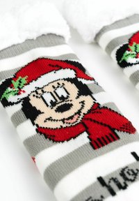 Calze a righe grigie e bianche con un design lavorato a maglia di un personaggio dei cartoni animati che indossa un cappello e una sciarpa rossa da Babbo Natale, con dettagli di agrifoglio.
